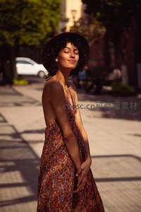 街头阳光下戴帽女子微笑转身