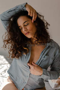 卷发女子慵懒床上伸展身姿