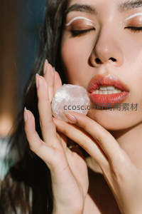 女性手持水晶轻触面颊妆容精致