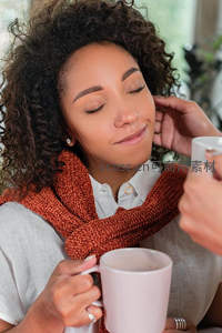 卷发女子闭目享受热饮，围巾温暖惬意时光