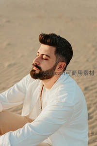 沙滩上闭目冥想的男子，沐浴金色夕阳