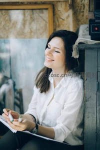 室内微笑女子手握笔本，享受创作时光