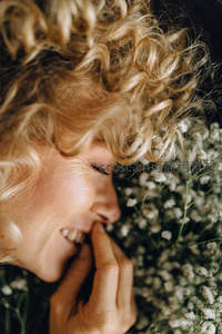 金发卷发女子微笑卧于满天星花丛中