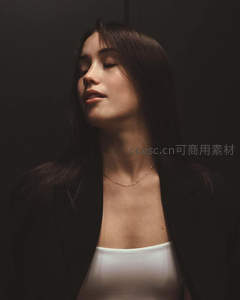 黑衣女子闭目沉思，光影勾勒优雅轮廓