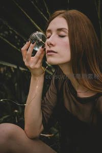 红发女子手持水晶球，林间光影梦幻如仙