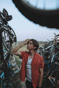 青年在废弃自行车堆中仰望天空
