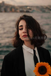 水边持向日葵女子，都市剪影衬托温柔神情