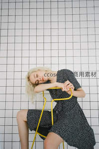 格子墙前倚椅小憩的波点裙少女