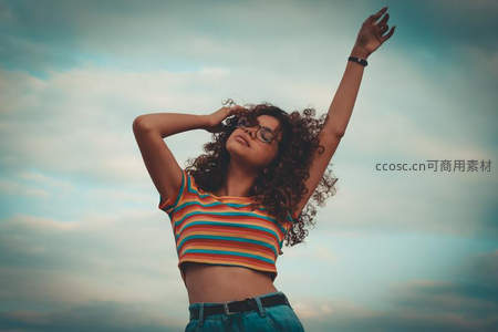 卷发少女仰望天空，彩色条纹上衣尽显活力
