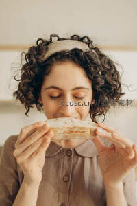 卷发女孩闭眼嗅闻新鲜面包香气，温馨治愈
