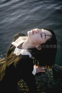 岩石边仰望天空的沉思少女