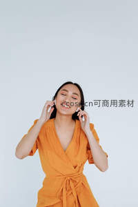 橙色连衣裙女子戴耳机微笑聆听