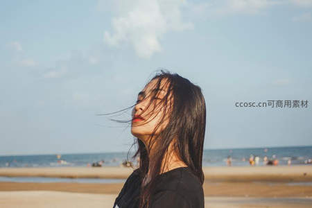 海风拂面，黑发女子闭眼享受海边时光