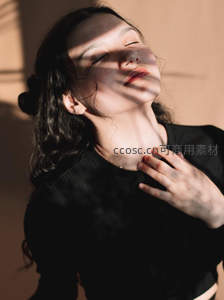 阳光洒落，黑衣女子享受温暖