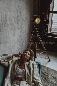 时尚模特在摄影棚内慵懒倚坐沙发