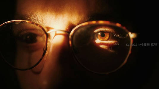 眼镜后的眼眸，暖光下的神秘凝视