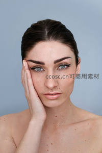 优雅女性轻抚面颊，眼神深邃