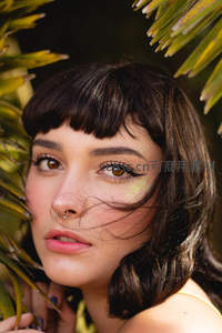 棕榈叶间凝视镜头的少女