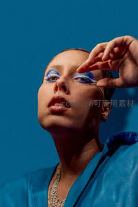 蓝色背景下创意眼妆与手势互动