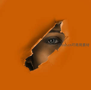 橙色纸洞中凝视的深邃蓝眼