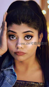 女孩手托脸颊凝望镜头，闪亮眼妆引人注目