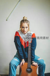 抱吉他少女坐姿沉静，街头风格尽显音乐气质