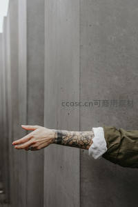 纹身手臂轻触灰色混凝土墙