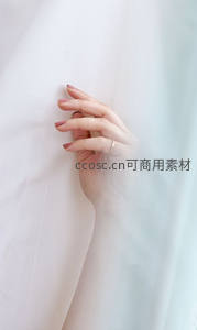 柔光中女性手轻抚白色布料