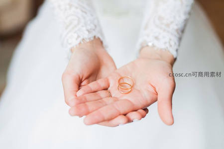 新娘手中捧着两枚金色婚戒