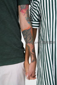 纹身手臂与条纹衣袖的亲密牵手