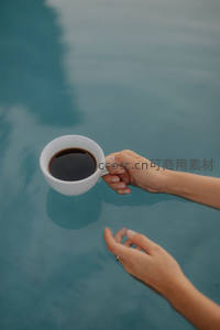 泳池边手持咖啡杯