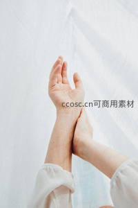 双手交叠于纯白布景前，传递温柔与呵护之意