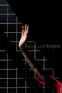 暗调瓷砖前举起的手，红衣与光影交织成戏剧性画面