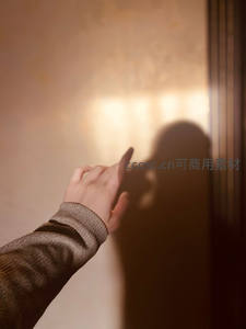 指尖轻触墙影，暖光下的静谧瞬间