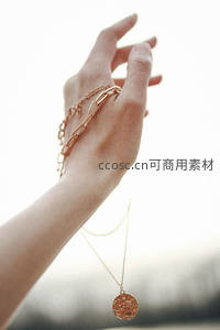 阳光下手腕轻托金色项链的优雅姿态