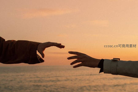 夕阳下两双手即将相触的温暖瞬间