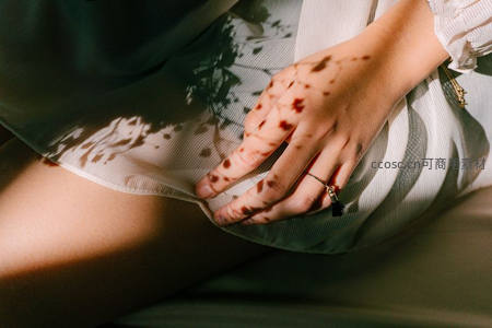 斑驳光影下轻抚裙摆的优雅手部特写