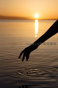 夕阳下伸手触水泛起涟漪的宁静瞬间
