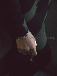 暗调中持烟的手腕，金属链扣彰显个性态度