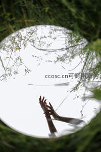 镜中倒影双手合十，草丛环绕如梦境