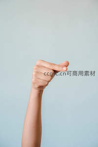 单手比出小指勾勾手势，简约背景下的俏皮互动