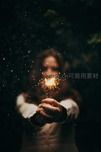 夜色中双手捧着闪烁的烟花棒