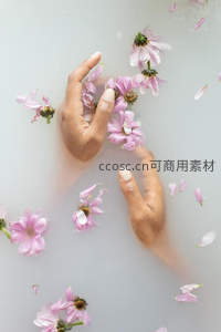 花瓣漂浮乳白浴水中，手轻触花蕊如梦似幻