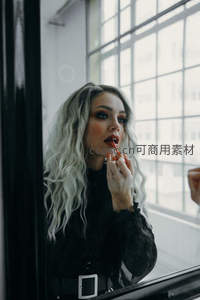 窗边银发女子涂抹红唇