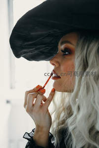 黑帽女子侧脸涂唇膏