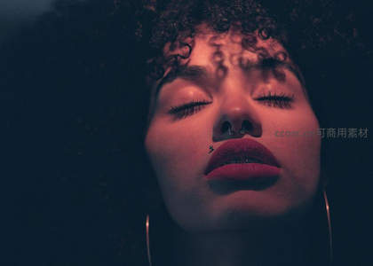闭眼卷发女子，红光映衬唇妆