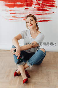 红唇女子手持电钻坐地，背景红白涂鸦墙