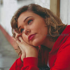 红衣卷发少女托腮凝望远方