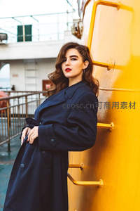 倚靠黄色船体的优雅风衣美人