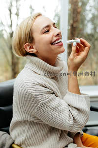 阳光下微笑女子，手持润唇膏享受惬意时光